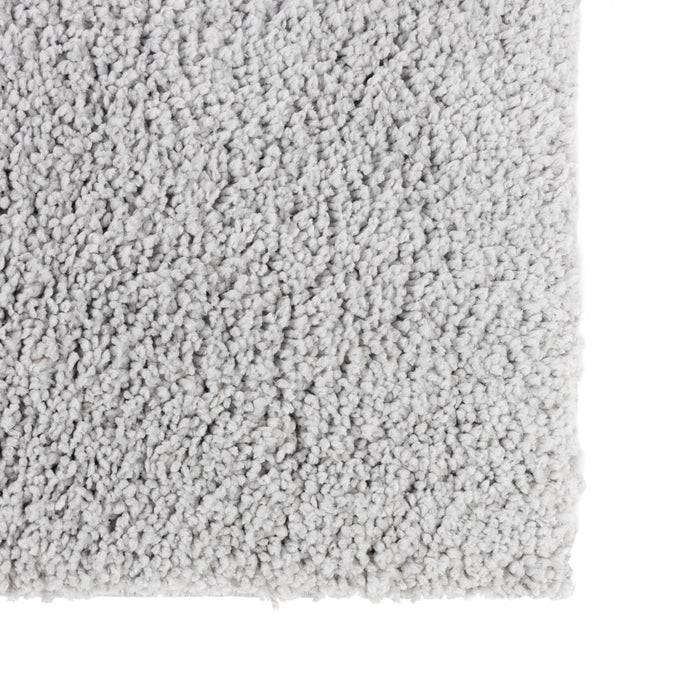 Nahaufnahme eines hellgrauen, weichen und texturierten Teppichs mit dichter Florhöhe, die seine üppige Oberfläche und gleichmäßige Faserverteilung zeigt.