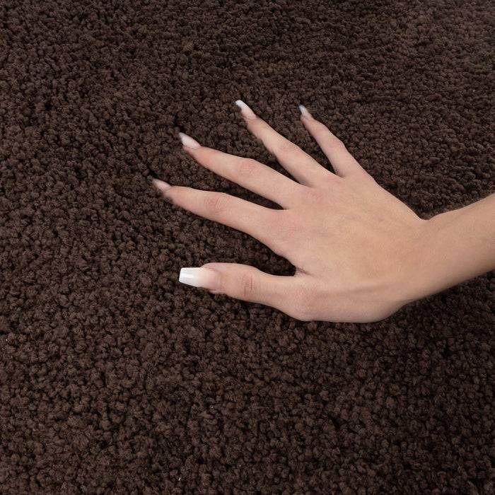 Eine Hand mit heller Hautfarbe und weiß lackierten Nägeln ruht auf einer texturierten braunen Oberfläche, möglicherweise ein zottelteppich oder Stoff.