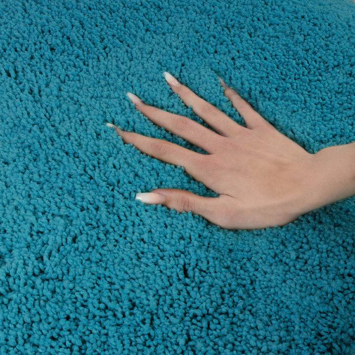 Eine Hand berührt behutsam einen strukturierten, hellblauen Teppich und veranschaulicht dessen weiche und üppige Beschaffenheit.