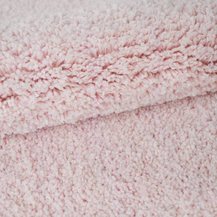 Nahaufnahme eines weichen rosa Plüschstoffs, die seine flauschige Textur und pastellfarbene Nuancierung zeigt, der häufig für gemütliche Decken oder Kleidungsstücke verwendet wird.