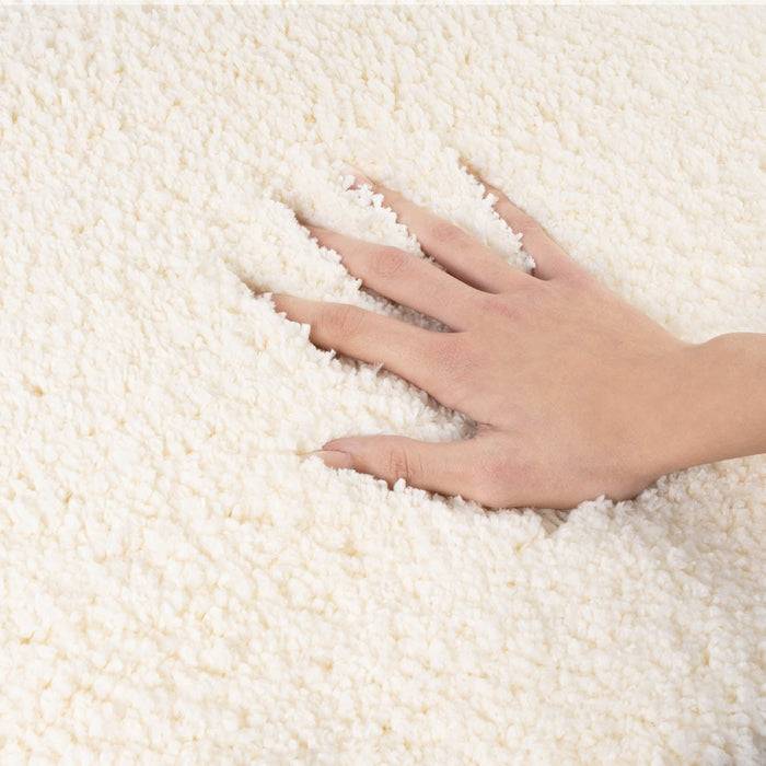 Eine Hand, die einen flauschigen weißen Stoff berührt und dessen weiche Textur betont.