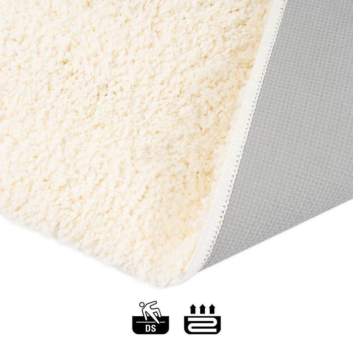 Nahaufnahme einer Matratzenecke, die ihre weiche, cremefarbene Oberfläche zeigt, mit Icons darunter, die auf rutschfeste und wärmespeichernde Eigenschaften hinweisen.