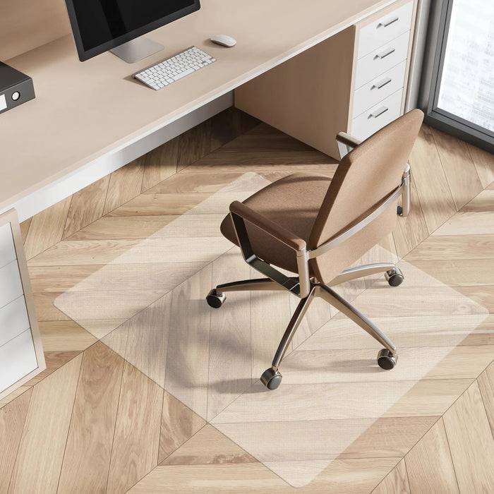 Ein ergonomischer Bürostuhl steht auf einer durchsichtigen Matte über einem Holzboden, positioniert vor einem Schreibtisch mit einem Computer, einer Tastatur und einer Maus.