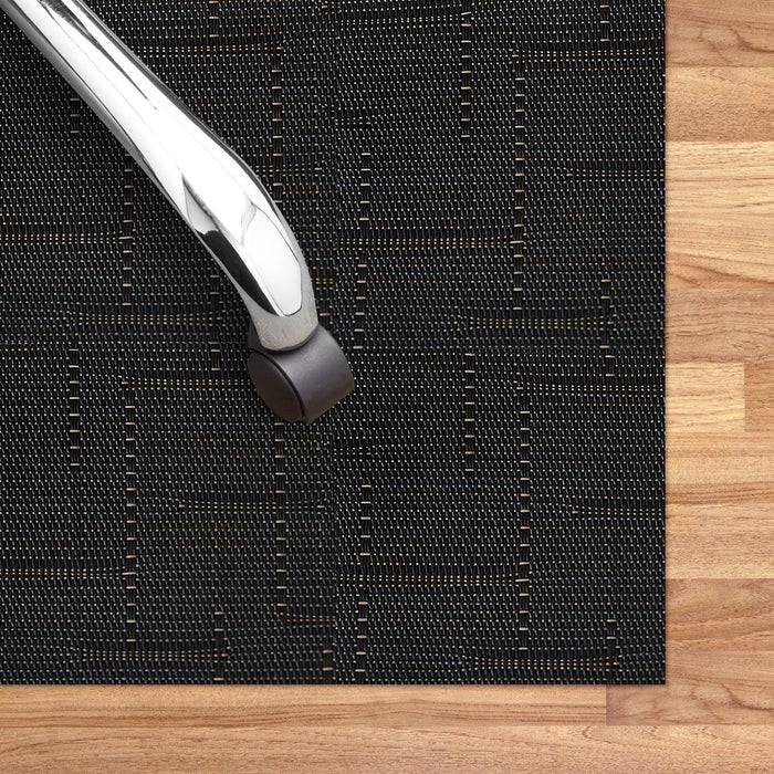 Bürostuhlrolle auf einer schützenden schwarzen Bodenmatte mit gewebter Textur, platziert auf Holzboden.
