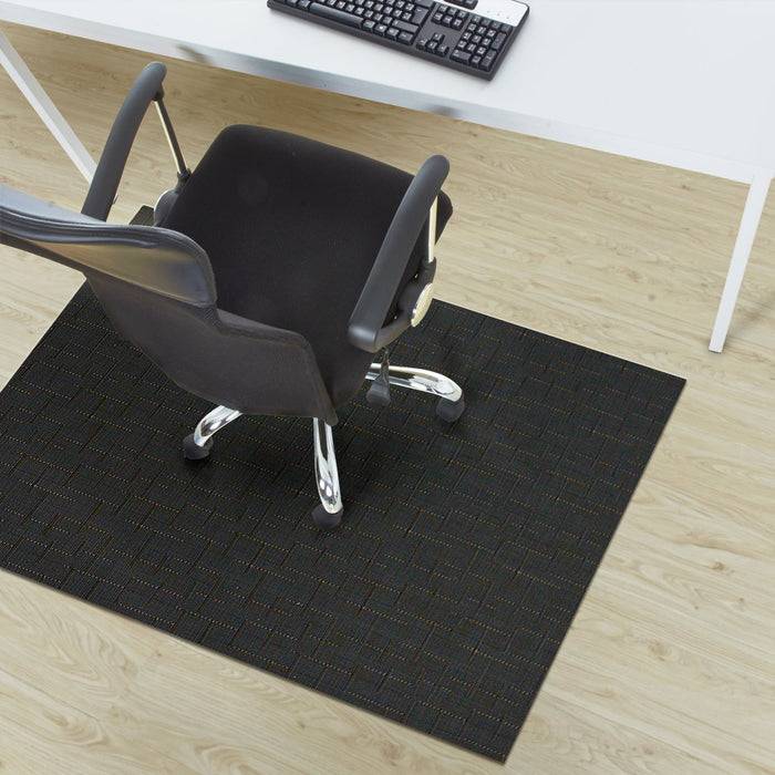 Bürostuhl auf einer Schutzmatte, die auf einem Holzboden platziert ist, positioniert vor einem weißen Schreibtisch mit einer Tastatur oben drauf.