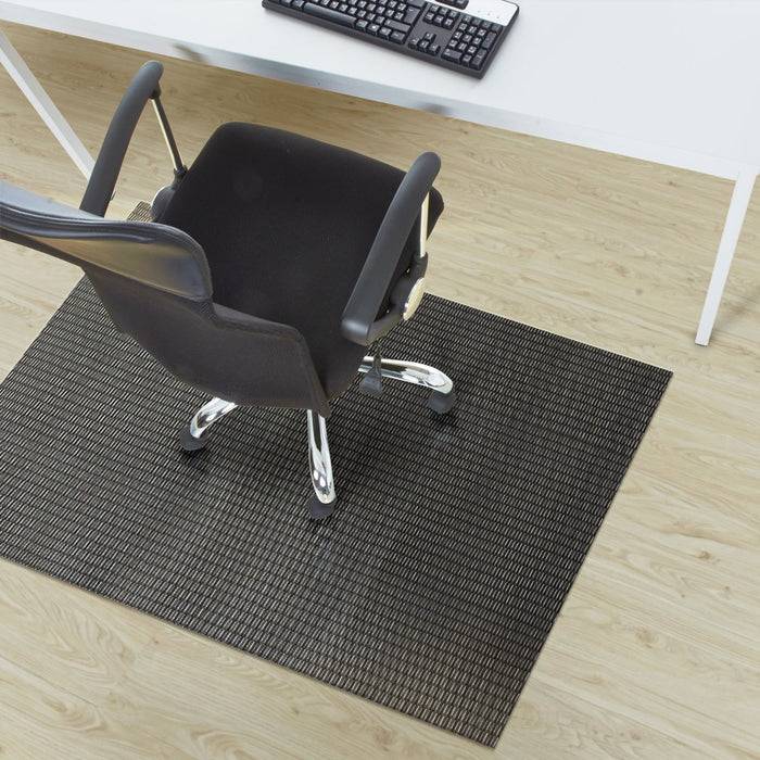 Bürostuhl auf einer schwarzen Matte unter einem Schreibtisch mit einer Computertastatur.