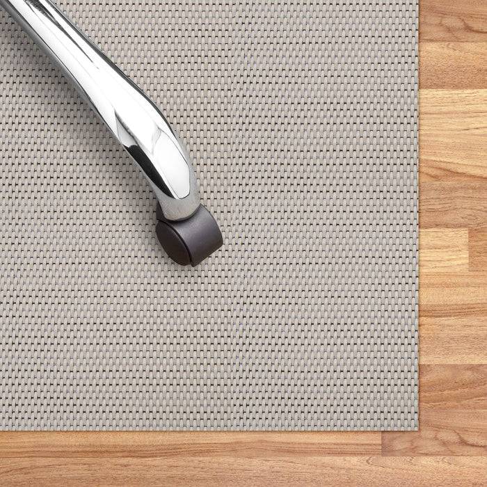 Bürostuhlrolle auf einer strukturierten grauen Schutzunterlage, die auf einem Holzfußboden ruht.