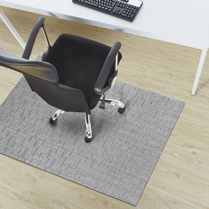 Ein Bürostuhl mit Rollen ist auf einer strukturierten Matte unter einem weißen Schreibtisch mit einer Tastatur positioniert, alles auf einem hellem Holzboden platziert.