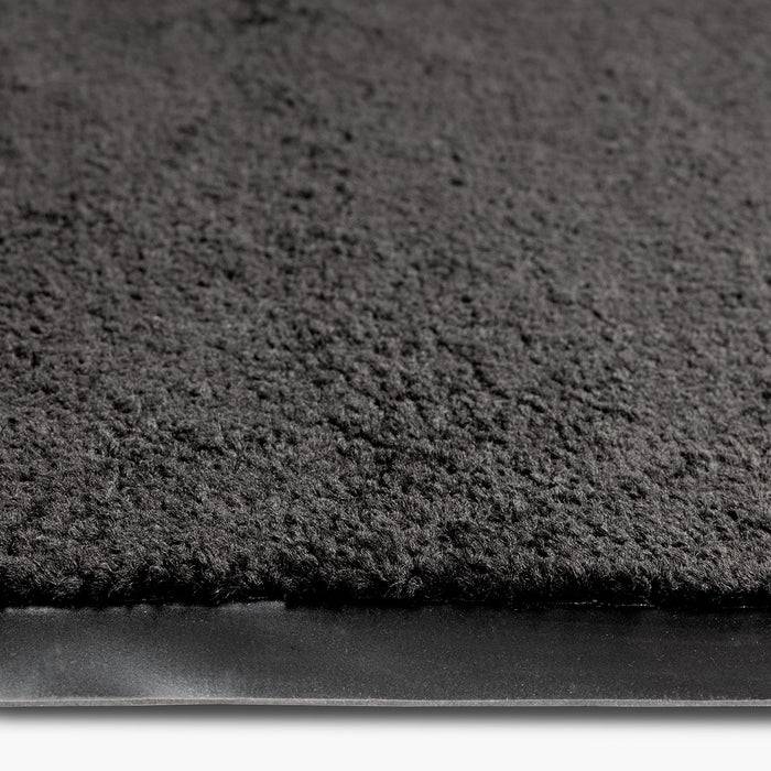 Nahaufnahme einer strukturierten schwarzen Teppichkante, die ihre Dicke und Materialdetails zeigt.