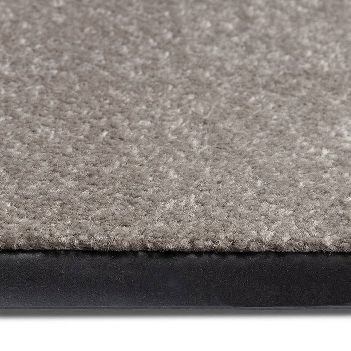 Nahaufnahme einer beigen Teppichkante mit schwarzer Gummirückseite.