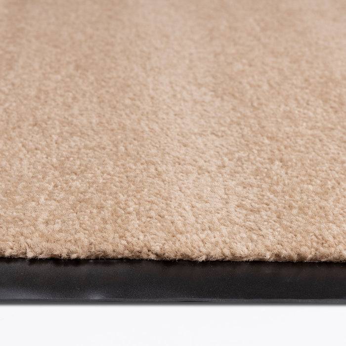 Eine Nahaufnahme eines beigefarbenen Teppichs mit schwarzem Gummirücken, der seine Textur und sein Material hervorhebt.