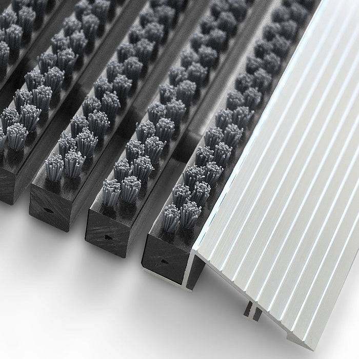 Detailaufnahme von schräg angeordneten Rillenwalzen und einer geschlitzten Metallplatte, höchstwahrscheinlich Komponenten eines Reinigungs- oder Filtrationsystems.