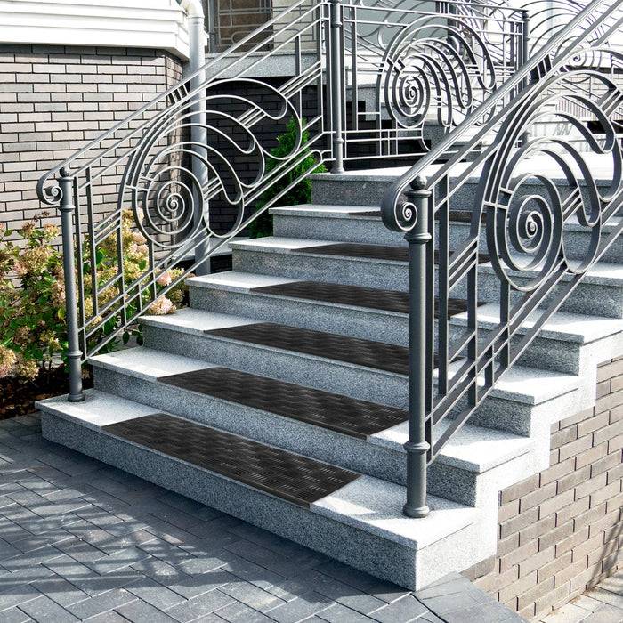 Aufwendige schwarze und silberne Metallgeländer schmücken eine Reihe von steinernen Treppen, die zu einem Gebäude führen, mit geometrischen Ziegelsteinmustern auf den Stufen.