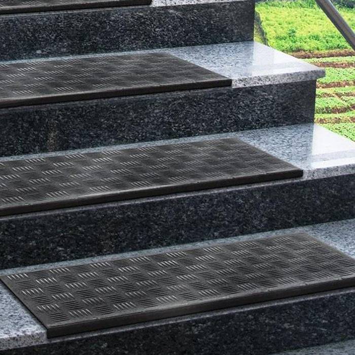 Schwarze rutschfeste Matten werden auf jeder Stufe einer Steintreppe platziert und sorgen für Sicherheit. Im Hintergrund ist Grünbewuchs zu sehen.