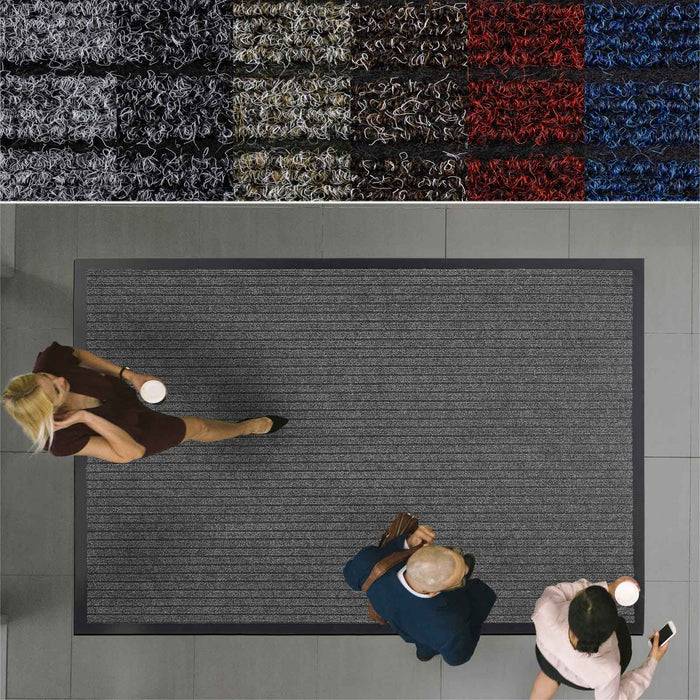 Drei Personen gehen auf einem strukturierten Teppich mit dunklen Streifen in einem Korridor.