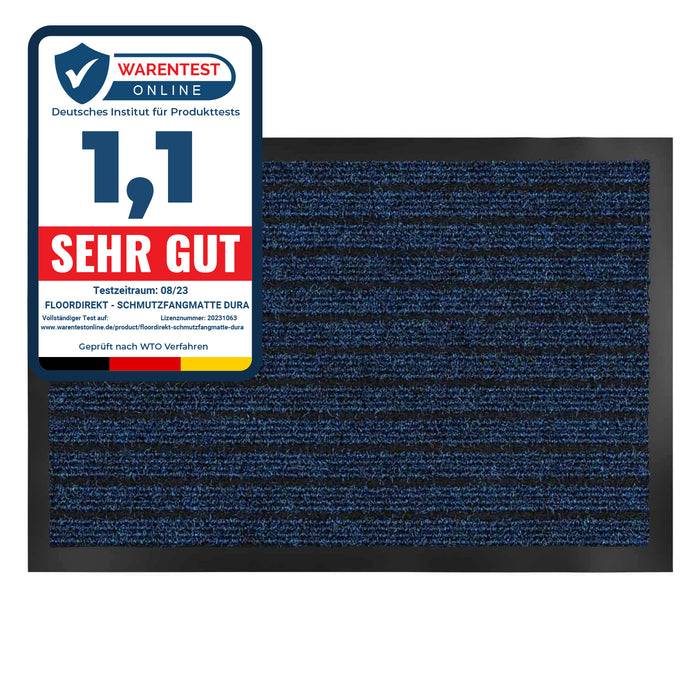Ein Produktbewertungsetikett mit 'SEHR GUT' Bewertung aus einem Testzeitraum im 08/23 auf einer blau-schwarz gestreiften Fußmatte.