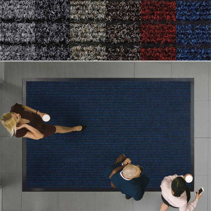 Drei Personen stehen auf einer blauen Fußmatte in einem gefliesten Raum. Mehrere farbige Fußmatten sind über ihnen an einem Wandpaneel ausgestellt.