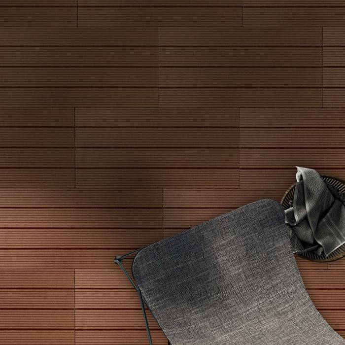 Eine strukturierte braune Wand mit einem modernen grauen Stuhl, der unten rechts teilweise sichtbar ist, schafft eine minimalistische und gemütliche Atmosphäre.