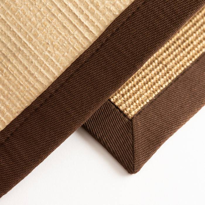 Strukturiertes beige- und braunes Stoffkissen mit Eckdetail, das gerippte und gewebte Muster zeigt und auf langlebige Handwerkskunst hindeutet.