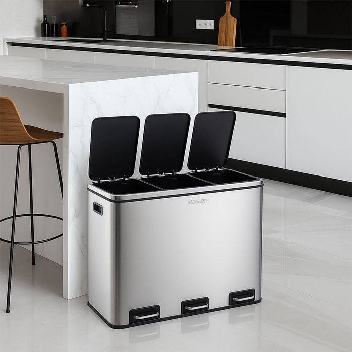 Eine moderne Küche mit einem Edelstahl-Mülleimer mit drei Fächern, jeweils mit einem Pedal, neben einer weißen Insel und einem Barhocker platziert.