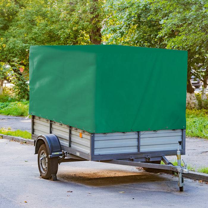 Ein kleiner, grün abgedeckter Nutzanhänger, der auf einer befestigten Fläche geparkt ist und von Bäumen umgeben ist.