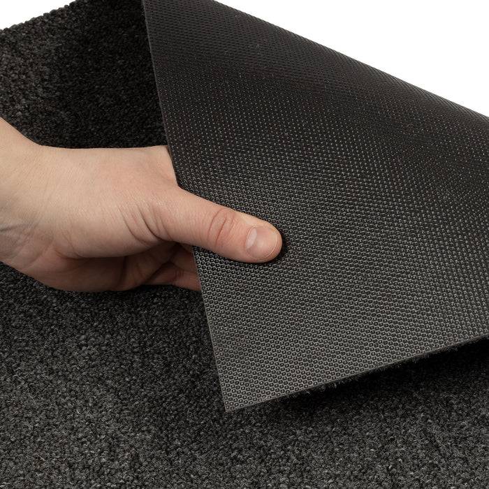 Ein modernes Wohnzimmer mit einem mauvefarbenen Sessel, zwei runden Tischen (einer mit Kannelüren, einer mit Büchern und einer Vase) und strukturiertem grauem Teppichboden.