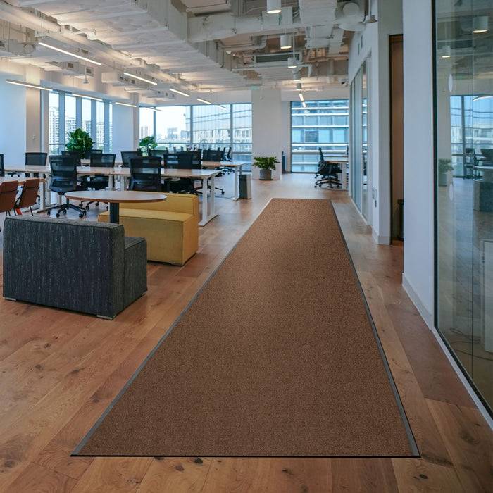 Ein modernes Büro mit großen Fenstern, offener Arbeitsfläche und mehreren Schreibtischen. Es gibt einen langen braunen Teppich auf dem Holzboden und Blick auf die Stadtlandschaft.