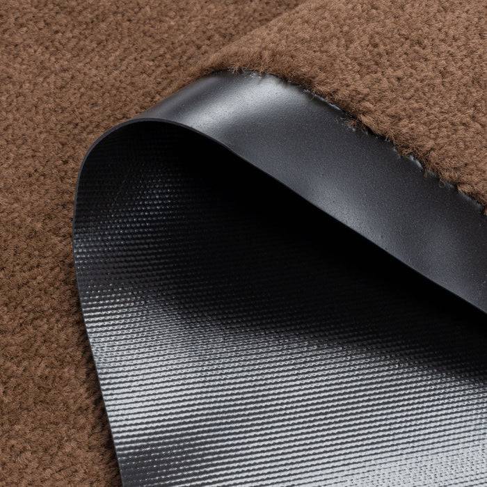 Eine Nahaufnahme eines braunen Teppichs mit schwarzer Gummirückseite, die die Textur und Materialschichten zeigt.
