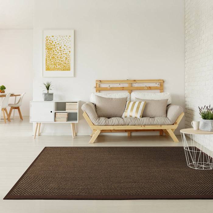 Ein modernes Wohnzimmer mit hellem Holzfußboden, weißem Sofa mit beigefarbenen Kissen, weißem Sideboard, gerahmter abstrakter Kunst und braunem Teppich.