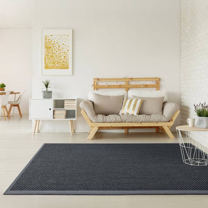 Ein modernes Wohnzimmer mit einem beigen Sofa, gestreiften Kissen, einem weiß und Holz Sideboard, abstrakten Wandkunstwerken und einem dunkelgrauen Teppich.