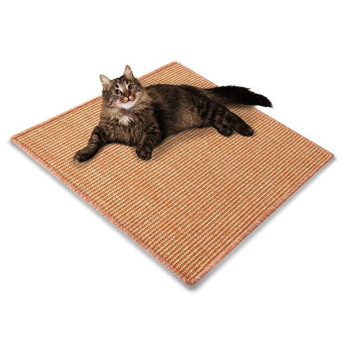Eine flauschige Katze liegt komfortabel auf einer strukturierten, quadratischen beigen Matte und schaut mit entspanntem Gesichtsausdruck nach oben.
