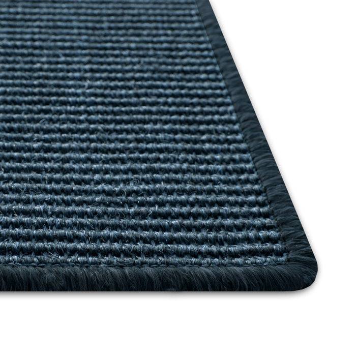 Eine Nahaufnahme einer rechteckigen blauen strukturierten Matte mit sauber gestepptem Rand, die detaillierte Webmuster und eine leicht erhobene Oberfläche zeigt.