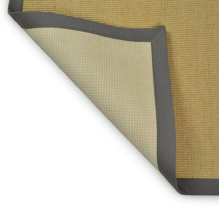 Ein beiger gewebter Teppich mit umgeklappter Ecke zeigt eine strukturierte graue Rückseite und unterstreicht das zweischichtige Design und den Farbkontrast des Teppichs.