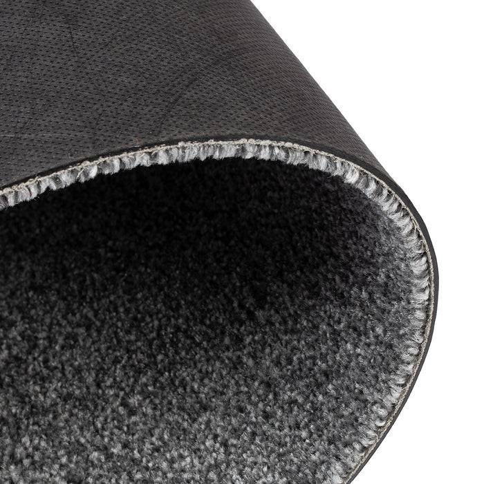 Eine Nahaufnahme der Ecke eines aufgerollten dunkelgrauen Teppichs, die die strukturierte Oberfläche und die gesäumten Kanten zeigt.