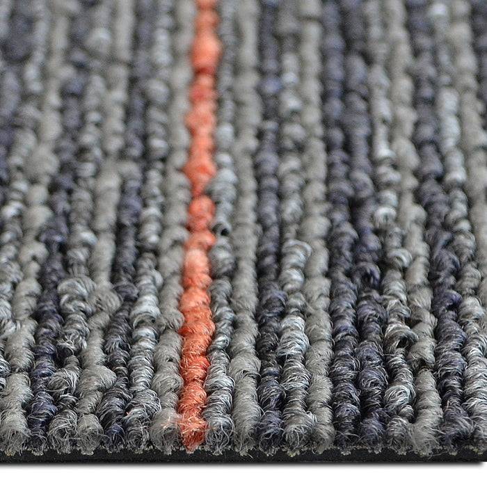 Eine Nahaufnahme einer strukturierten, gerauten Teppichoberfläche mit einer Mischung aus Grau, Dunkelgrau und einem einzelnen roten Streifen, der vertikal verläuft.