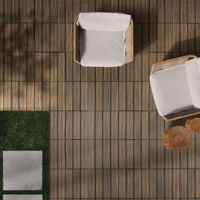 Draufsicht auf zwei gepolsterte Stühle auf einem Holzdeck mit einem kleinen Baumstumpftisch zwischen ihnen, angrenzend an einen Bereich mit Gras und Pflastersteinen.