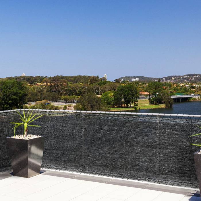 Blick von einem Balkon über einen friedlichen Fluss, umgeben von Grün. Im Vordergrund steht ein dekorativer Blumentopf.