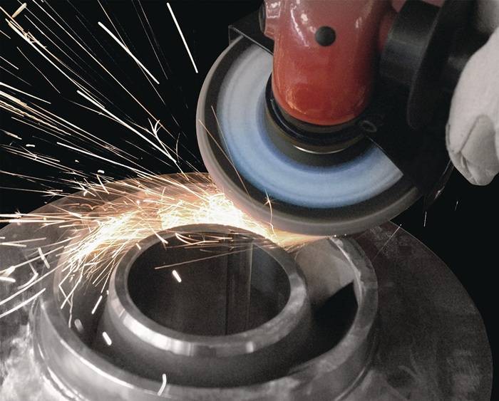 Ein Nahaufnahme zeigt ein Metallschleifwerkzeug, das Funken auswirft, während es an einem kreisförmigen Metallstück arbeitet und damit industrielle Verarbeitung hervorhebt.