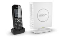 Schwarzes schnurloses Handset auf Ladebasis neben weißem Snom-Wireless-Gerät auf Ständer, gezeigt vor einfachem Hintergrund.