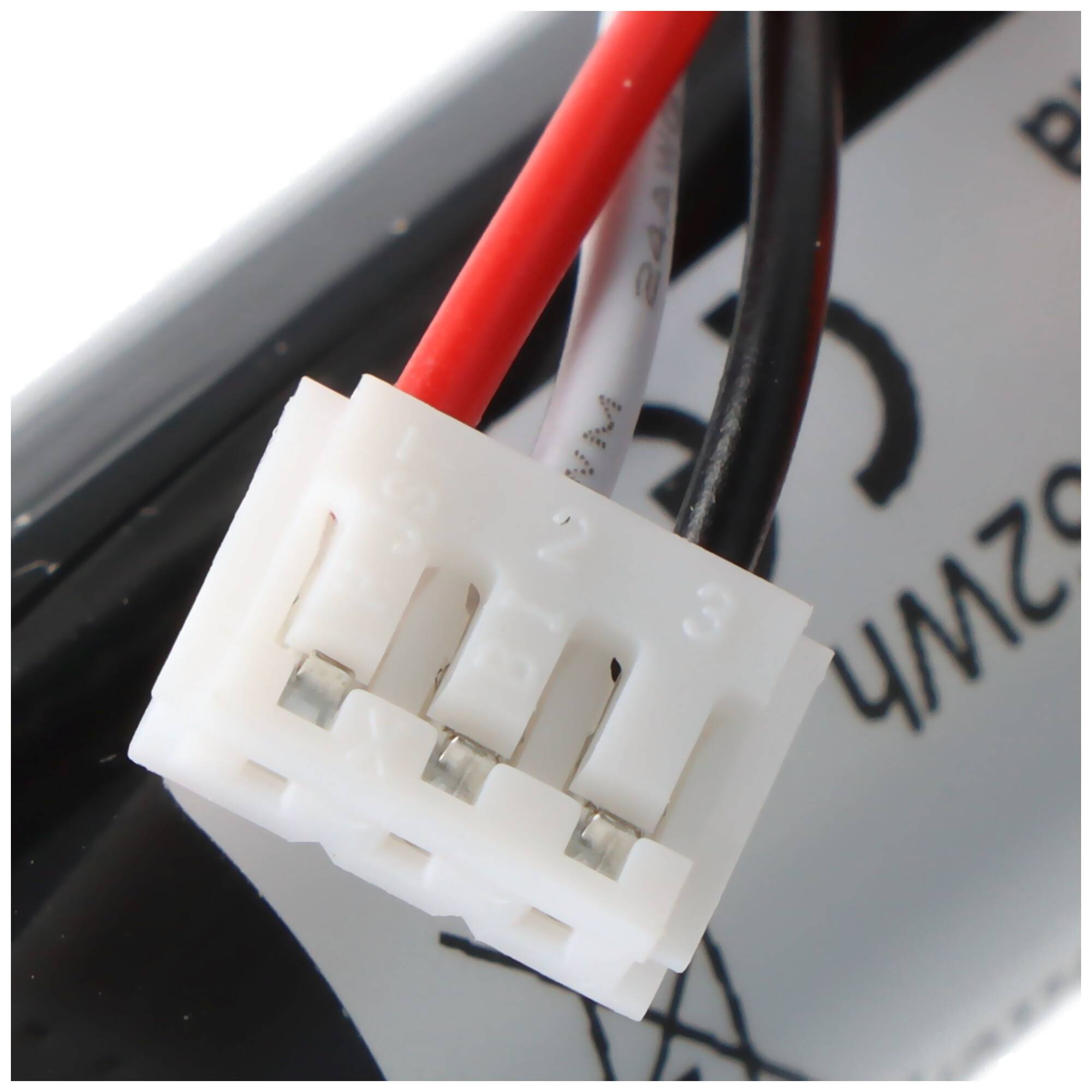 Eine Nahaufnahme eines weißen elektronischen Steckers mit vier nummerierten Anschlüssen und angeschlossenen roten und schwarzen Drähten vor einem teilweise sichtbaren Hintergrund.