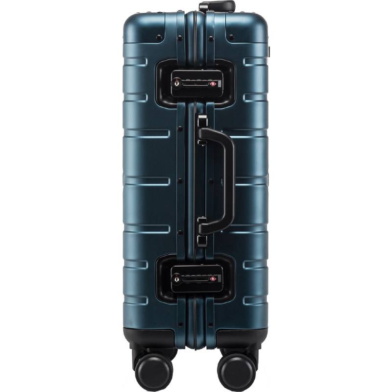 Ein blauer Hartschalenkoffer mit einem stabilen Griff und vier Rollen, aufrecht stehend.