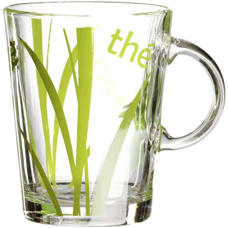 Ein durchsichtiger Glasbecher mit grünem Grasmuster und teilweisem Text 