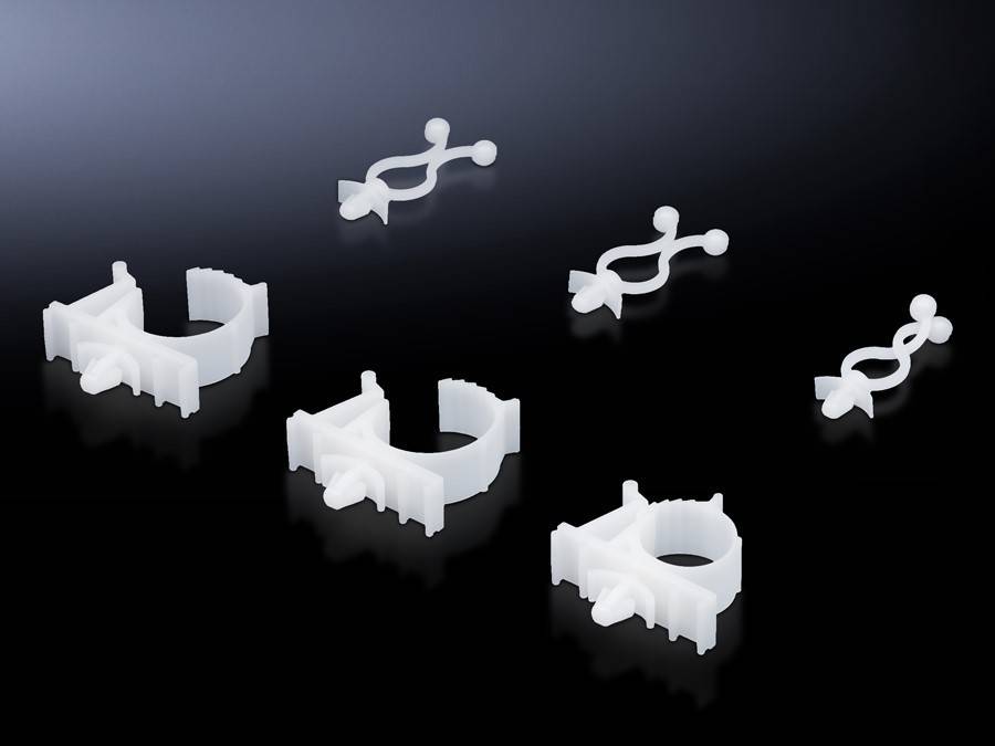 Verschiedene weiße Kunststoff-Rohrklemmen sind auf einer dunklen, reflektierenden Oberfläche angeordnet. Sie variieren in Größe und Form und sind zum Befestigen von Rohrleitungen konzipiert.