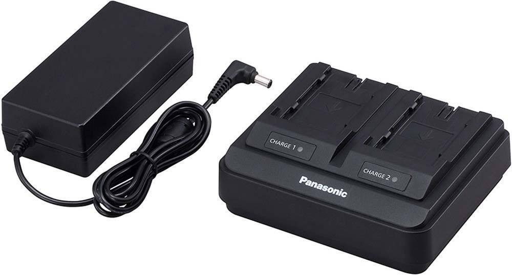 Ein dualer Batterieladegerät mit der Bezeichnung 'Panasonic' mit Steckplätzen für 'Ladung 1' und 'Ladung 2', zusammen mit einem Netzadapter und Netzkabel.