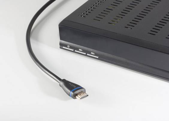 Nahaufnahme eines HDMI-Kabels, das an der Rückseite eines schwarzen elektronischen Geräts angeschlossen ist, mit sichtbaren Stromversorgungs- und Anschlussanzeigeleuchten.
