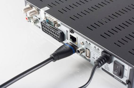 Nahaufnahme der Rückseite eines elektronischen Geräts mit angeschlossenen VGA-, Ethernet- und Stromkabeln, zeigt hintere Eingabeanschlüsse und Netzschalter.