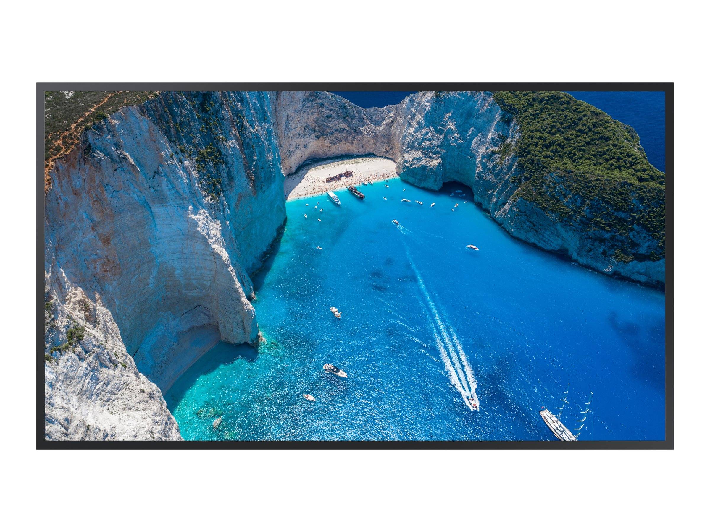 Luftaufnahme von Booten in einer leuchtend blauen Bucht neben steilen weißen Klippen und einem kleinen Sandstrand.