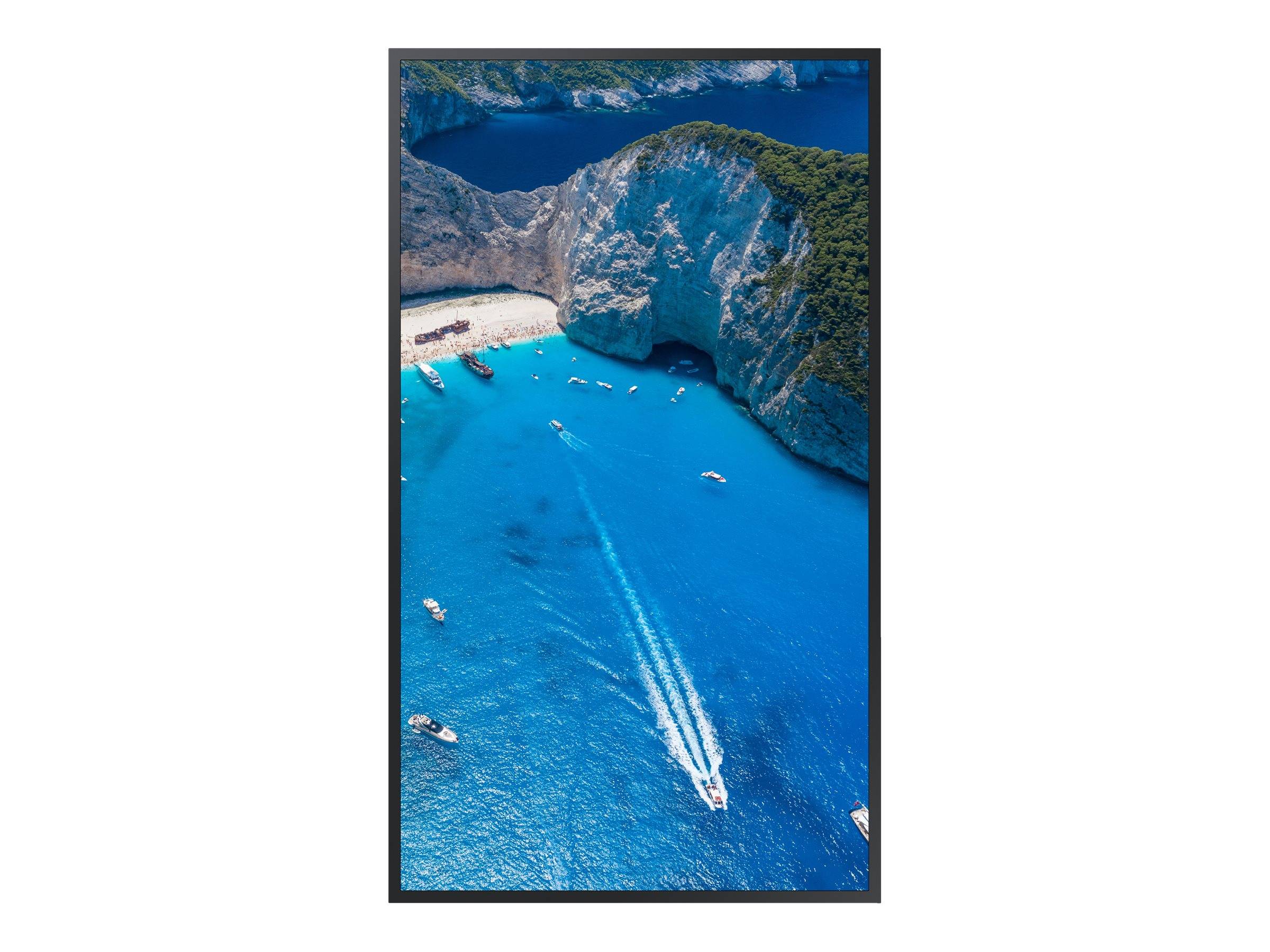 Luftaufnahme einer türkisfarbenen Bucht mit steilen weißen Klippen, einem kleinen Strand und mehreren Booten, die weiße Kielwasser im Wasser hinterlassen.