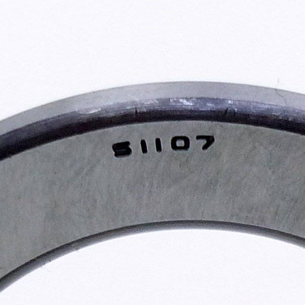 Nahaufnahme eines grauen Metallrings oder Lagers mit dem gestempelten Code 'S1107' in der Nähe der oberen Kante.
