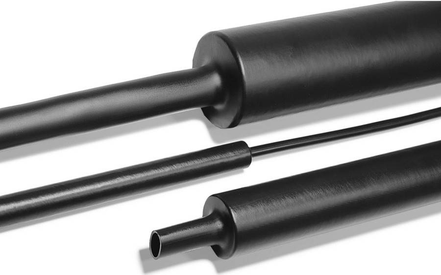 Nahaufnahme von drei schwarzen Rohren unterschiedlicher Durchmesser und Längen, diagonal auf weißem Hintergrund ausgerichtet.